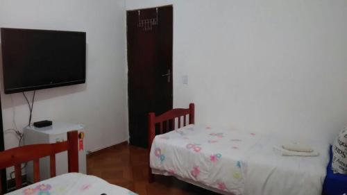 a bedroom with two beds and a flat screen tv at Pousada Bluesky in Barueri
