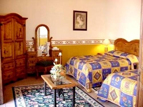 a bedroom with two beds and a table at Hotel Reyna Soledad in Zacatecas