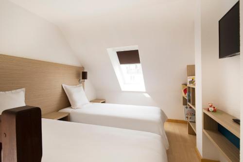 two beds in a small room with a window at Escale Oceania Saint Malo in Saint Malo