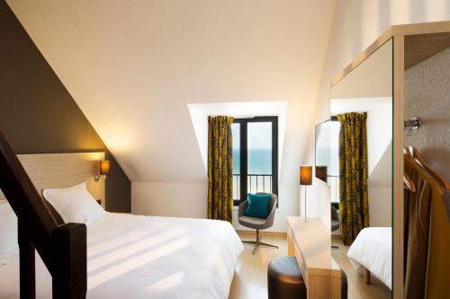 a hotel room with a bed and a chair and a window at Escale Oceania Saint Malo in Saint Malo