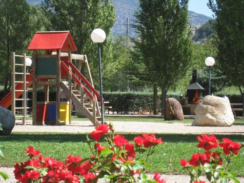 un parque infantil con tobogán en un parque con flores rojas en Apartamentos Naspún, en Campo