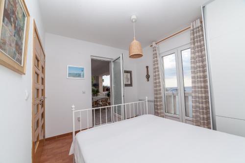 a white bedroom with a bed and a window at Beachfront First Line View in Sveti Stefan