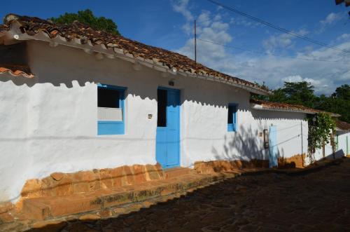 una casa blanca con puertas azules en una calle en Albahaca Hospedaje Tienda, en Barichara