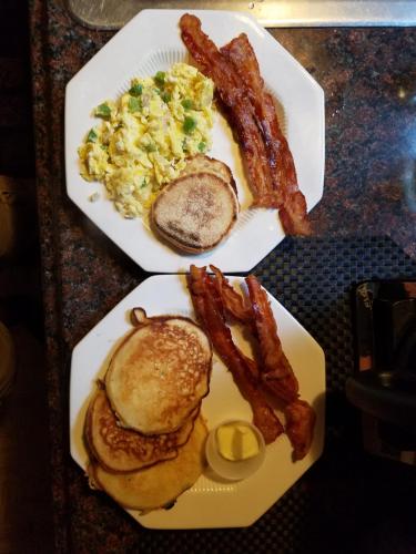 two plates of breakfast food with bacon and eggs at Kountry Living Bed and Breakfast in Oneonta