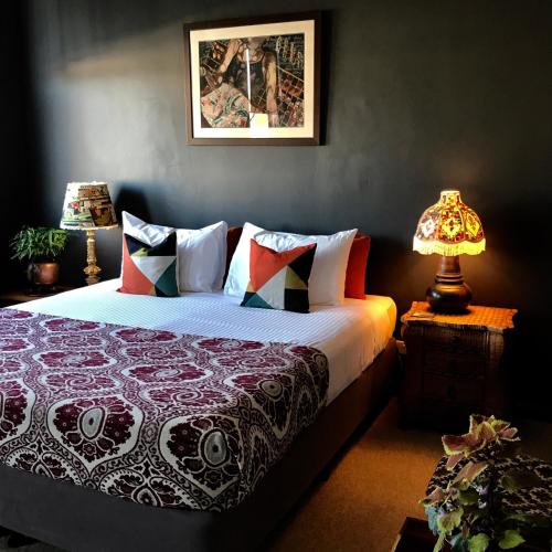a bedroom with a bed and a lamp on a table at Vine Valley Inn in Cessnock
