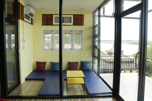 a room with a table and chairs on a balcony at Mekong Tarawadee Villa in Tha Bo