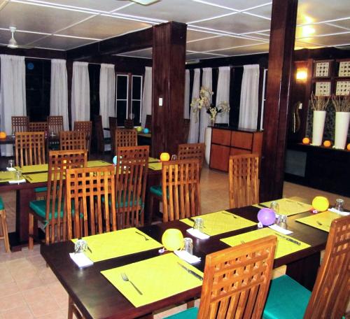 un comedor con mesas y sillas con servilletas amarillas en Raintree Lodge, en Port Moresby