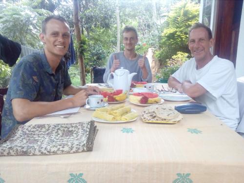 Un gruppo di uomini seduti a un tavolo con del cibo di Hidden Gem Inn a Ella