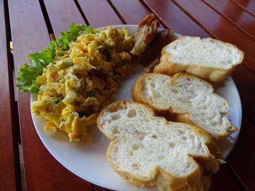 Un plato blanco con huevos, pan y ensalada. en Ratanakiri Paradise Hotel & Restaurant, en Banlung