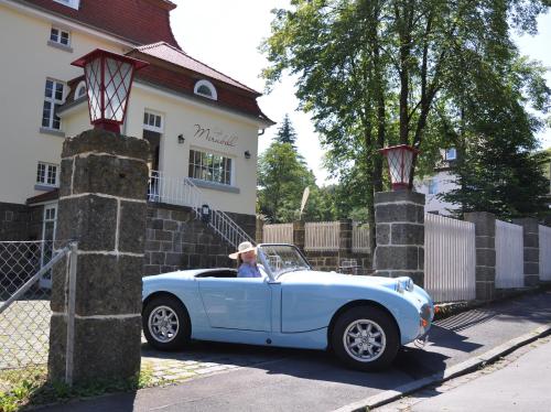 a man driving a blue car in front of a house at Villa Andante Apartmenthotel in Kassel