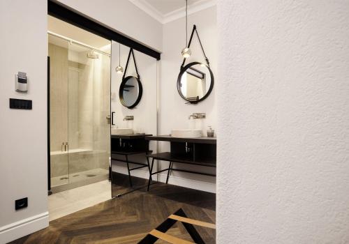 a bathroom with a sink and two mirrors on the wall at Kollmann Rooms and Apartments in Ljubljana