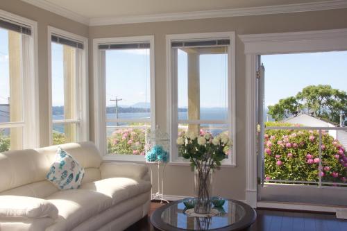 a living room with a couch and windows with flowers at Star of the Sea guest house in White Rock