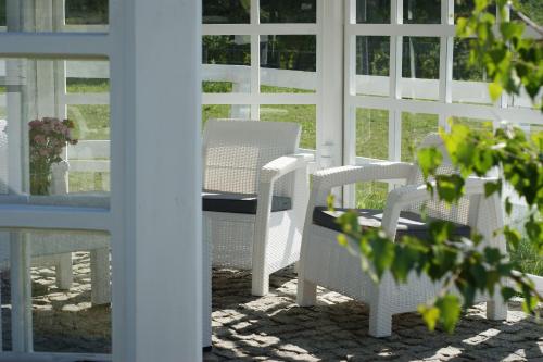- une terrasse couverte avec des chaises blanches et une table dans l'établissement Gościniec Husarski, à Sandomierz