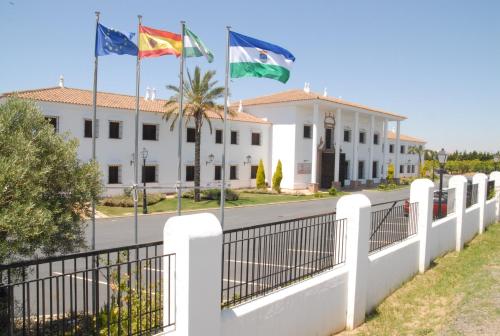 Una valla blanca con tres banderas delante de un edificio. en Hotel Valsequillo, en Lepe