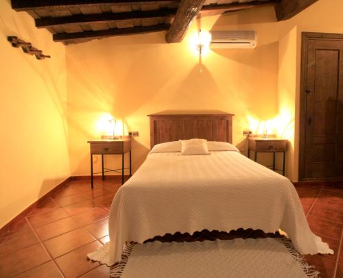 a bedroom with a white bed and two night stands at La Boticaria Casa Rural Apartamento in Descargamaría