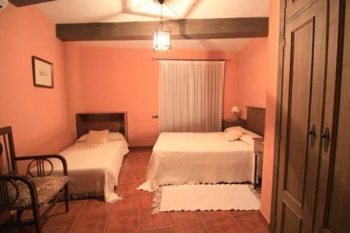 two beds in a room with pink walls at La Boticaria Casa Rural Apartamento in Descargamaría