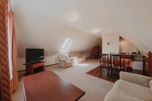 a living room with a couch and a tv at Hotel Cesarski - Kaiserhof in Giżycko