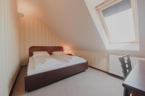 a bed in a small room with a window at Hotel Cesarski - Kaiserhof in Giżycko