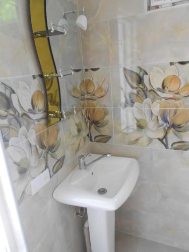 a bathroom with a sink and flowers on the wall at Marina kvariati in Kvariati