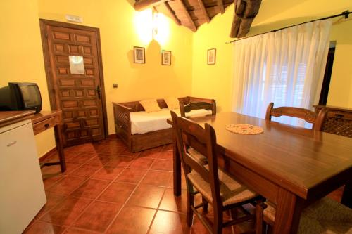 a kitchen and dining room with a table and a couch at La Boticaria Casa Rural Apartamento in Descargamaría