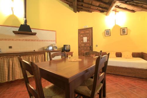 a dining room with a wooden table and a bed at La Boticaria Casa Rural Apartamento in Descargamaría