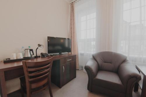 a room with a desk with a chair and a television at Hotel Cesarski - Kaiserhof in Giżycko