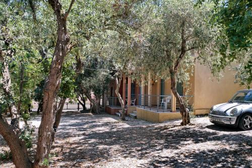 a car parked in front of a building with trees at Pefka Rooms in Mytilini