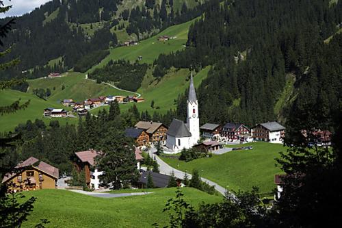 a small village with a church in a green field at Alpin Chalet Schröcken in Schröcken