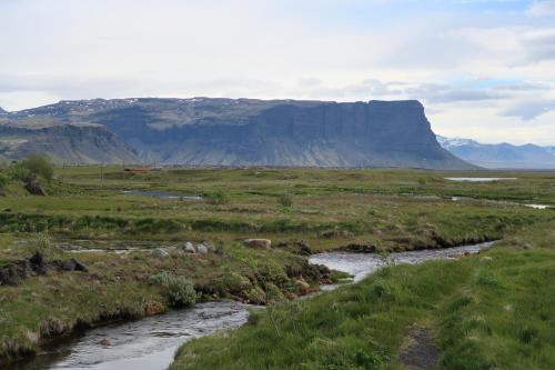 un río en un campo con una montaña en el fondo en Hvoll Hostel, en Kirkjubæjarklaustur