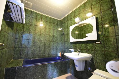 a green tiled bathroom with a sink and a tub at Green 58 B&B in Hengchun South Gate