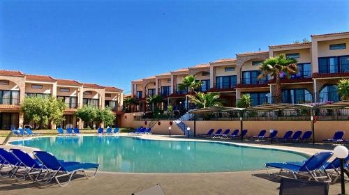 a large swimming pool with blue chairs and buildings at Village Mare in Metamorfosi