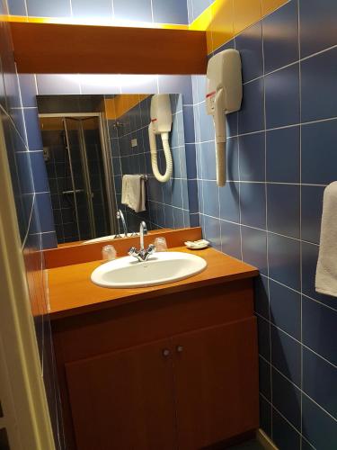 une salle de bain avec un lavabo et un miroir dans l'établissement Hotel Le Saint Georges, à Riom-ès-Montagnes