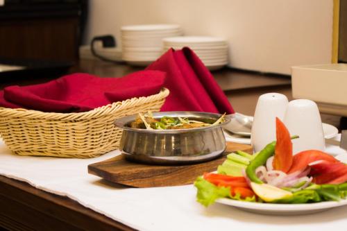 a table with a plate of food and a bowl of salad at S Chalet Islamabad in Islamabad