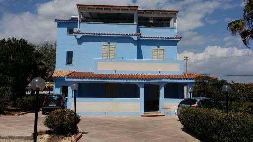 a blue building with cars parked in front of it at Villa Azzurra Scale of the Turks in Realmonte