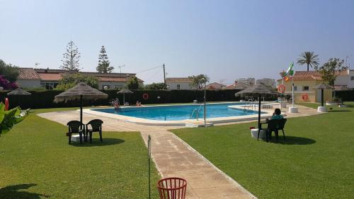 トレモリノスにあるHolidays2Torremolinos Apartamento de 3 dormitorios con terraza y piscina comunitariaのスイミングプール横の椅子に座る者