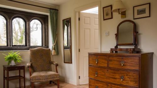 a room with a dresser and a mirror and a chair at Biggin Hall Country House Hotel in Hartington