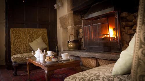a living room with a fireplace and a table with teaisers at Biggin Hall Country House Hotel in Hartington