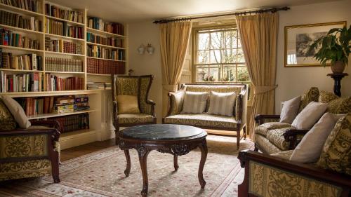 Biggin Hall Country House Hotel في هارتنغتون: غرفة معيشة مع طاولة وكراسي ورفوف كتب