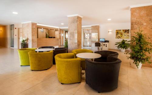 a lobby with yellow chairs and tables in a building at Apartamentos Sol y Vera in Magaluf