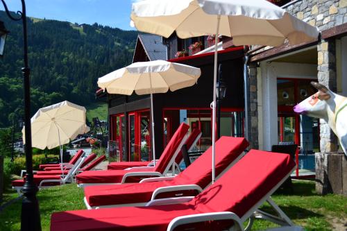 a row of red lounge chairs and umbrellas at Hôtel Alpina & SPA - Restaurant Oxalis in Les Gets