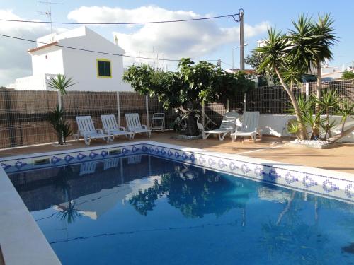 a swimming pool with chairs and a house at Casa São José by Pérola do Oceano in Manta Rota