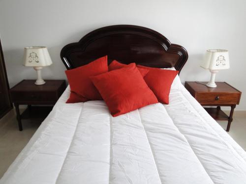 a bed with red pillows on it with two night stands at Pérola do Oceano in Manta Rota