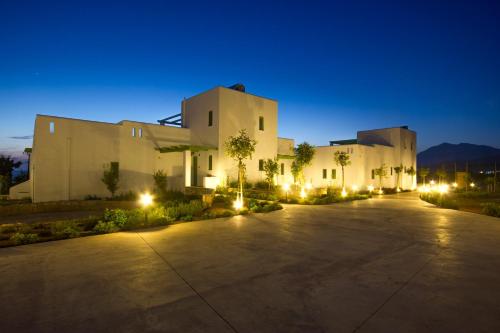 a large white building with lights at night at Alona Luxury Villas in Arkasa