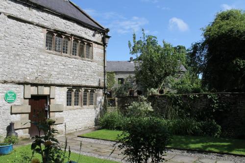 an old stone building with a garden in front of it at Biggin Hall Country House Hotel in Hartington