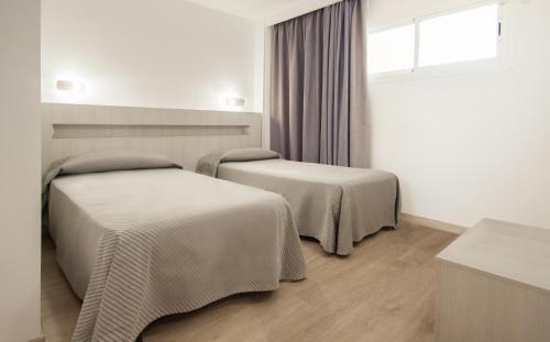 two beds in a room with a window at Apartamentos Sol y Vera in Magaluf