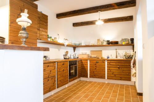 a kitchen with wooden cabinets and a tile floor at Henye holiday homes in Balatonhenye