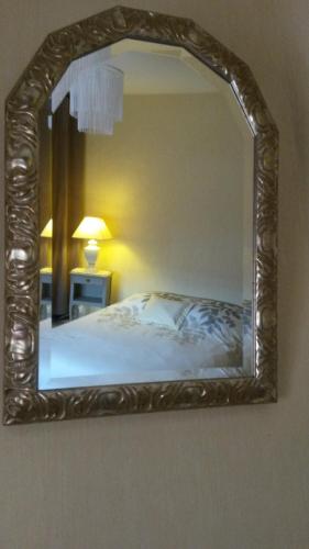 espejo en una pared sobre una cama en un dormitorio en Route de voivres, en La Suze-sur-Sarthe