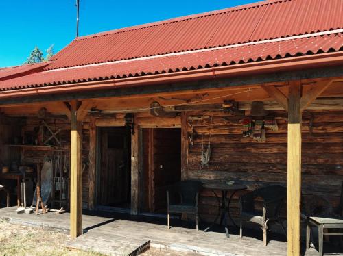 a wooden cabin with two chairs and a red roof at Guest House Viesu Māja Klētnieki in Ģipka