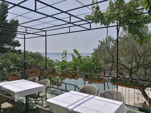 a patio with tables and chairs and a view of the ocean at Rooms Ante in Tribanj-Krušćica