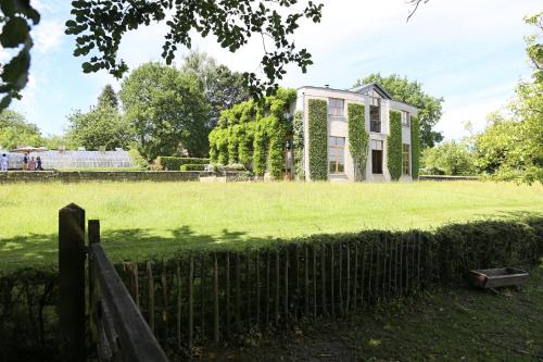 a house in a field with a fence at Le Jardin Des Sources in La Hulpe